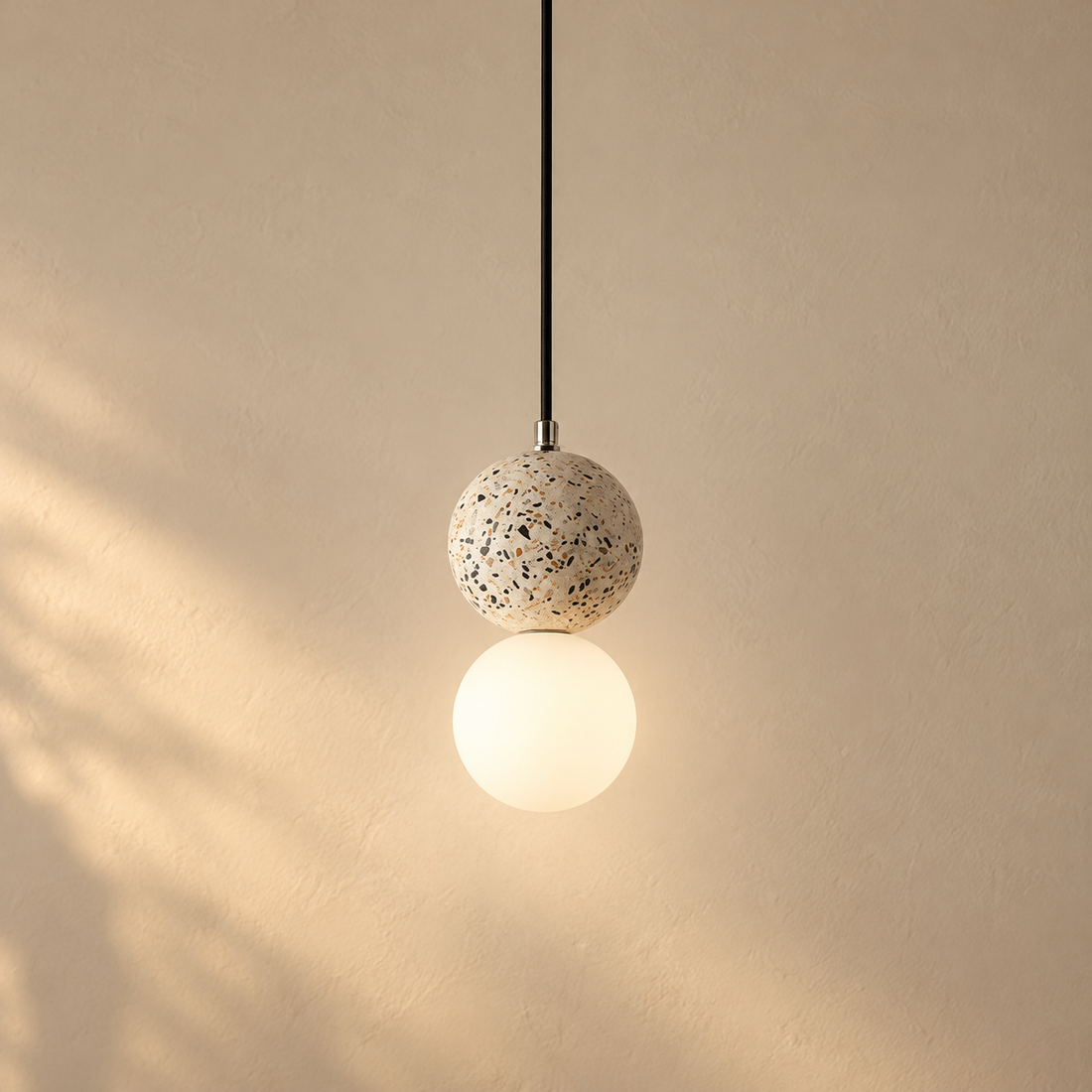 Terrazzo Globe Pendant Light illuminated against cream plaster