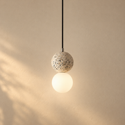 Terrazzo Globe Pendant Light illuminated against cream plaster
