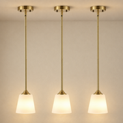 Brushed Brass 3-Light Pendant with White Glass Shades illuminated against cream plaster