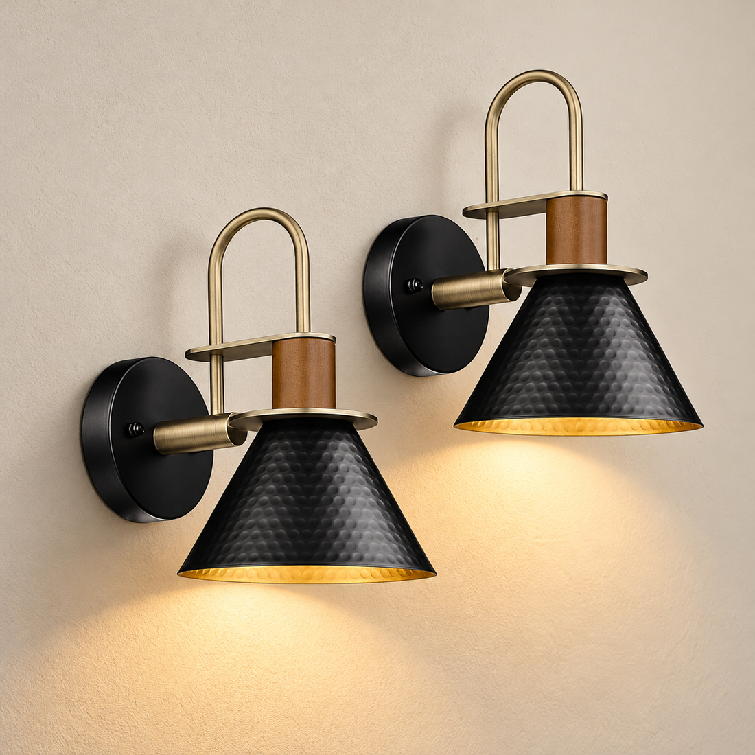 Black and gold gooseneck wall sconces, set of two, illuminated against cream plaster