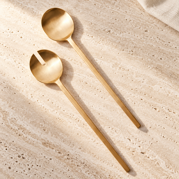 Pure Brass Salad Serving Spoon & Fork Set on a sunlit pale travertine counter