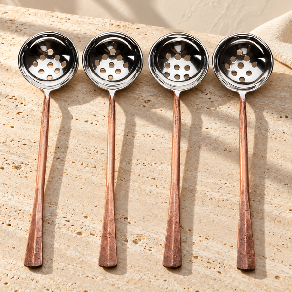 Copper-Finish Perforated Olive Spoon Set on a sunlit pale travertine counter
