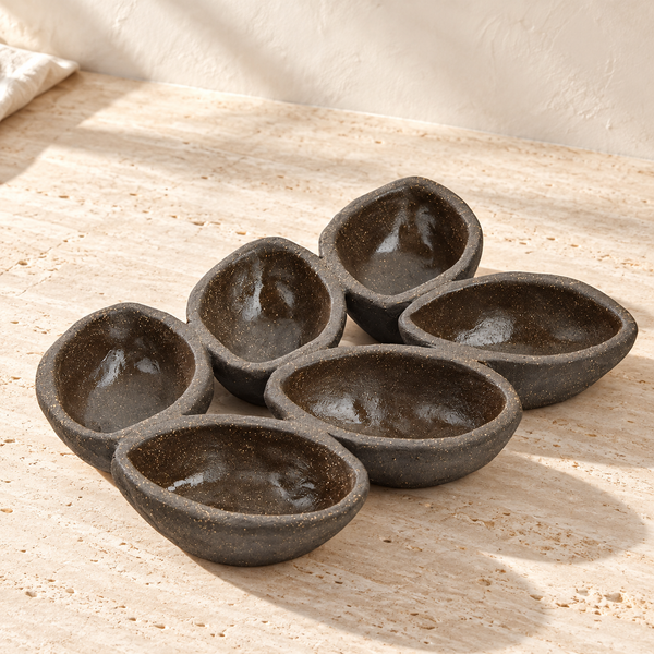Dark Stoneware Six-Well Serving Dish on a sunlit pale travertine counter