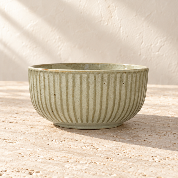 Cream Glazed Ribbed Stoneware Serving Bowl on a sunlit pale travertine counter