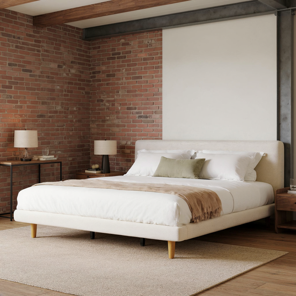 Cream Upholstered Platform Bed Frame Cal-King styled with ivory bedding in a brick and steel loft bedroom with a flat oatmeal rug.
