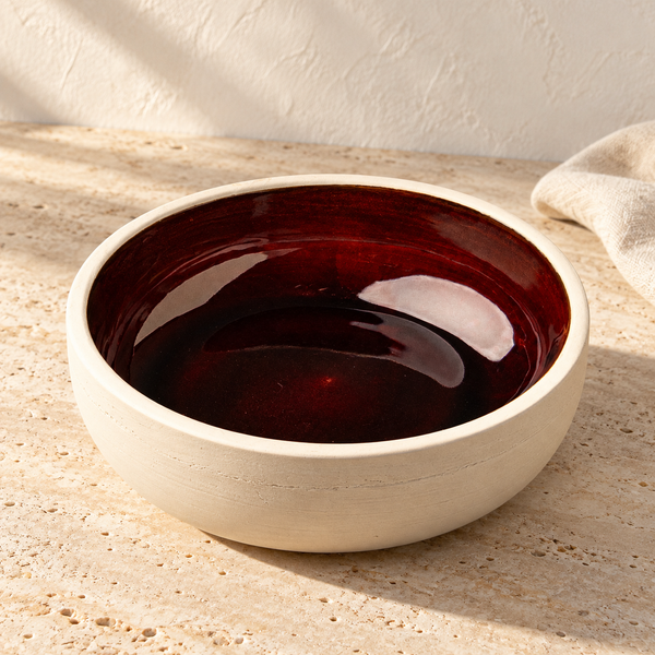 Glazed Ceramic Dinner Bowl in Sangre on a sunlit travertine counter