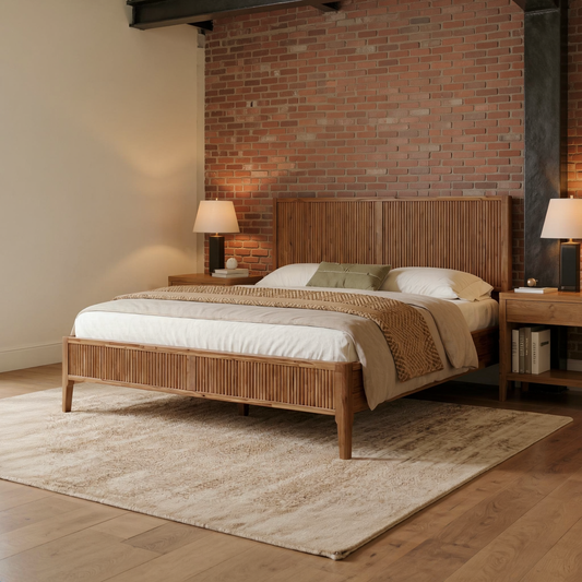 Walnut fluted acacia wood bed frame with ivory bedding, shown at an angle in a brick loft bedroom with a flat oatmeal rug