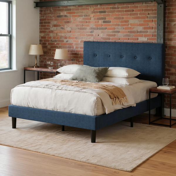 Navy button-tufted platform bed with ivory bedding and camel throw, shown at an angle in a brick loft bedroom with a flat oatmeal rug.