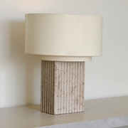 Fluted Travertine Base Table Lamp on a neutral concrete tabletop