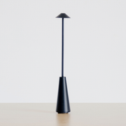Matte Black Portable Rechargeable Table Lamp on a neutral concrete tabletop