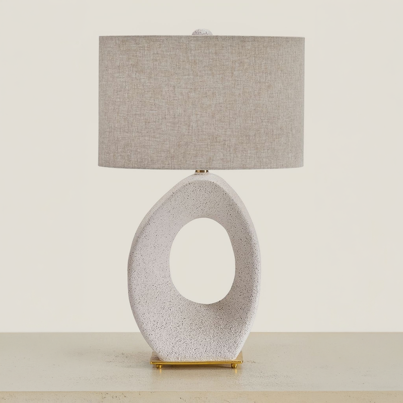 Cream and gold paper table lamp with an open oval base on a neutral tabletop