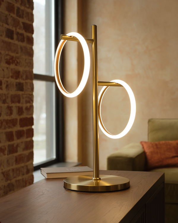 Brass Saturn table lamp with two illuminated rings on a walnut console in a warm brick loft