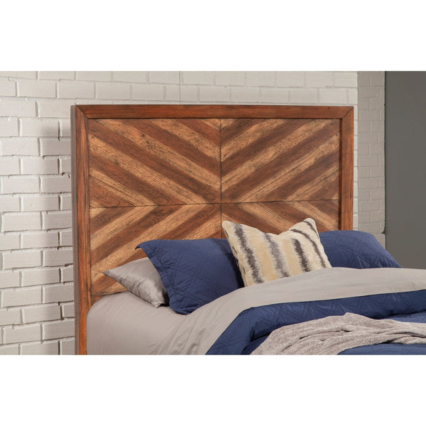 Close-up of brown chevron headboard behind blue pillows against white brick.